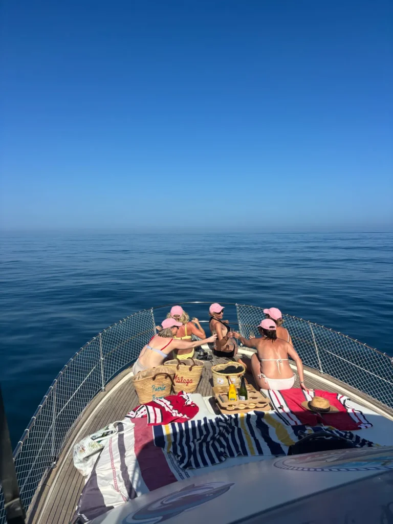 Amigas tomando el sol y brindando en la proa del Le Flot Riant V en una celebración en barco en Estepona
