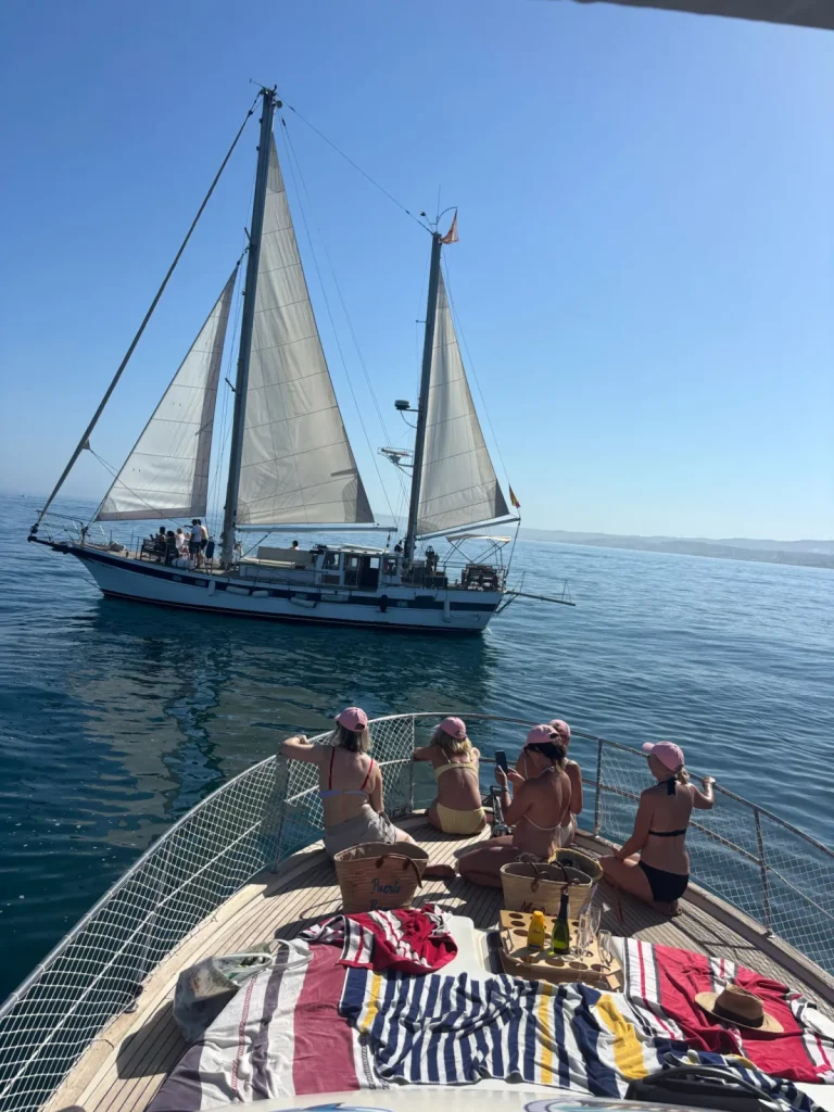 Grupo con picnic en la proa del Le Flot Riant V y un velero al fondo, celebración en barco privado en Estepona